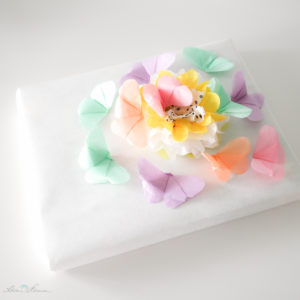 Geschenkverpackung mit Pompon und Schmetterlingen aus Seidenpapier